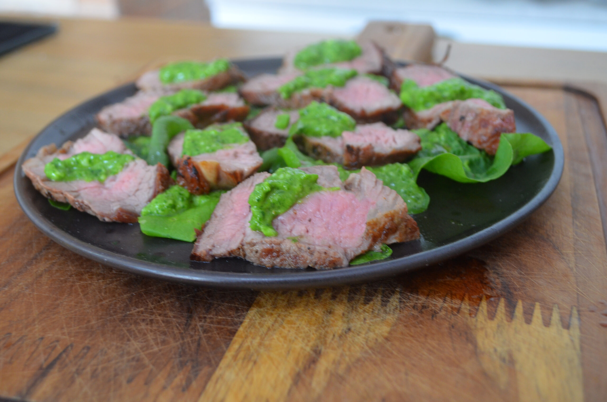 Maminha suculenta na churrasqueira acompanhada de pesto de rúcula servido em um prato rústico com pão tostado.