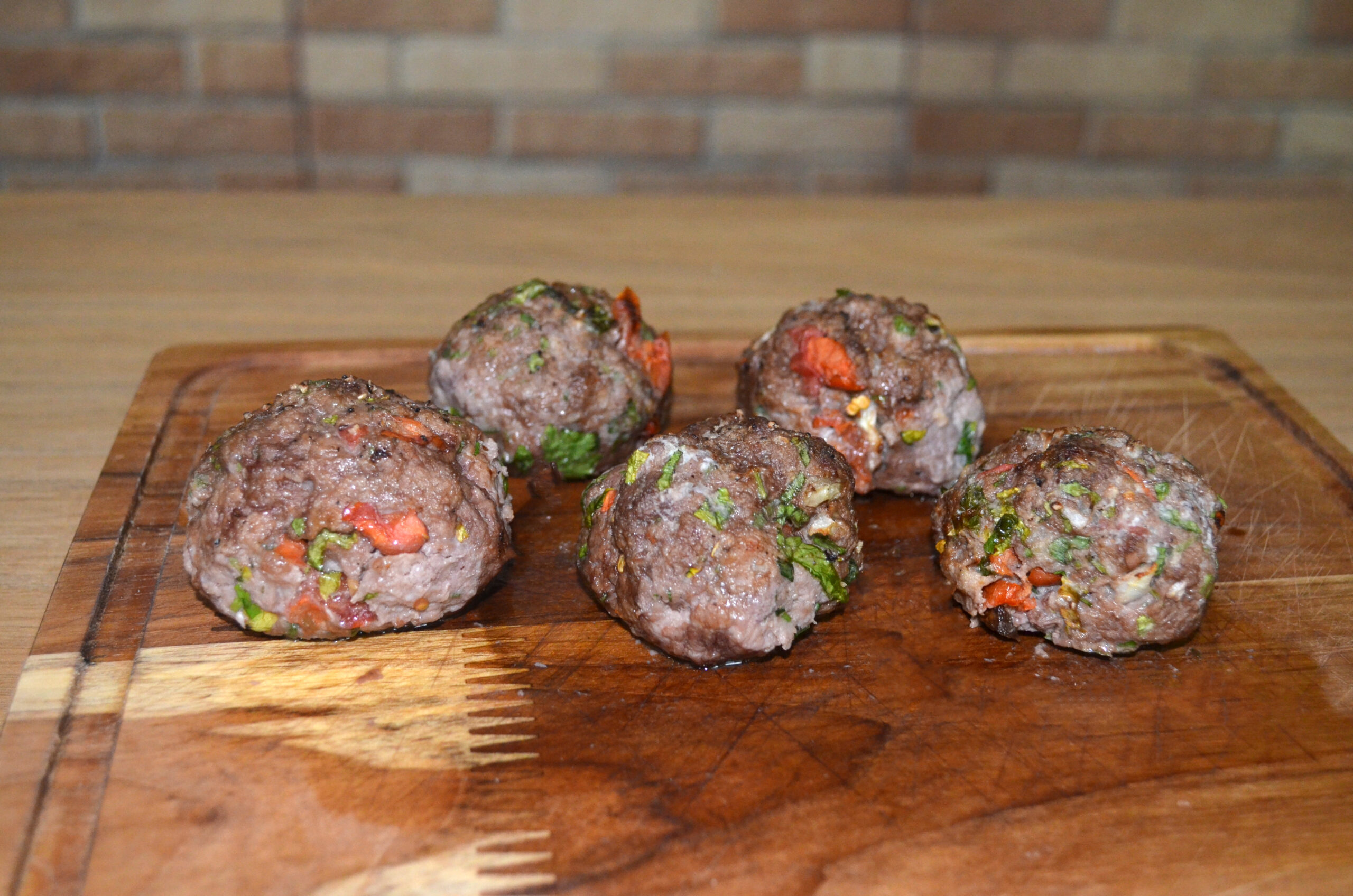 Bolinhos de carne dourados servidos em uma travessa, com salsinha picada como decoração.