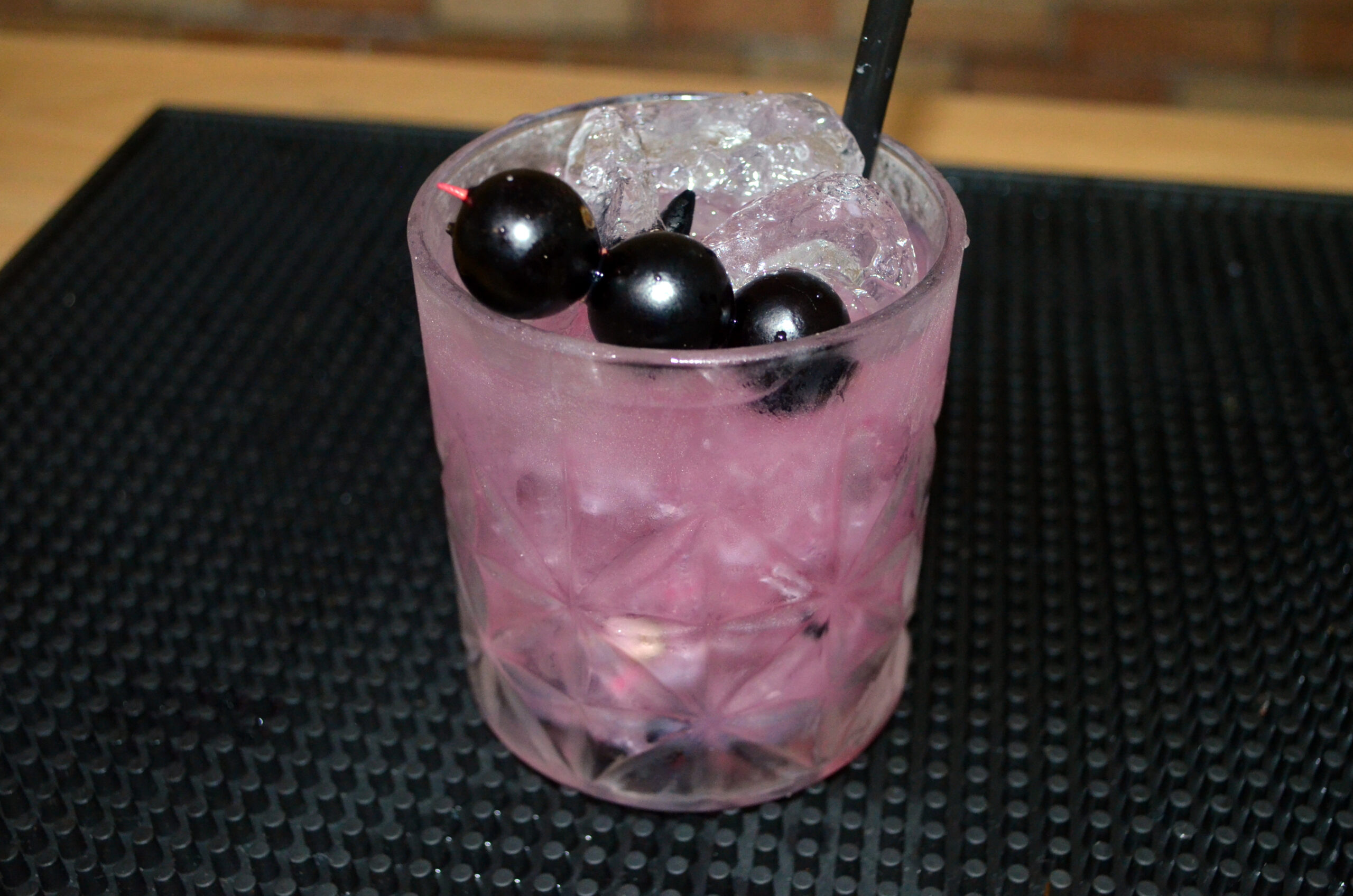 Copo de caipirinha de jabuticaba decorado com jabuticabas no palito e gelo picado.
