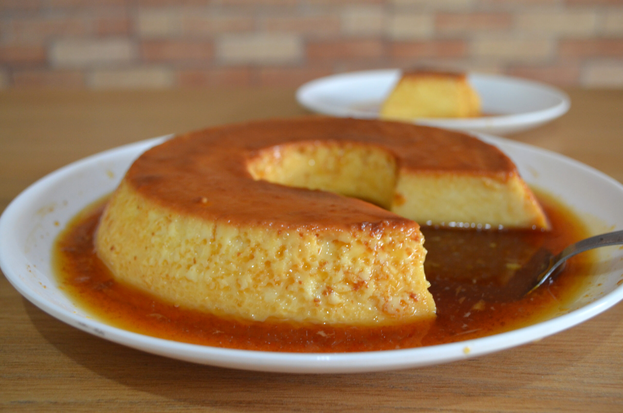 Pudim com leite condensado caramelizado e desenformado em prato de servir."