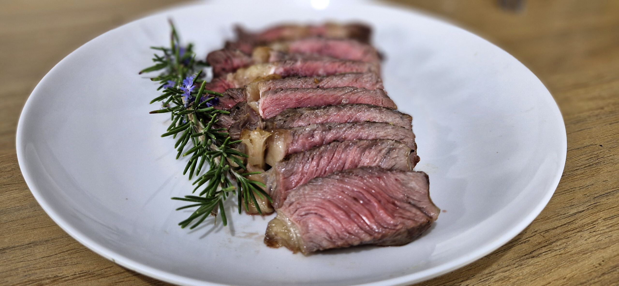 Bife ancho suculento preparado na Airfryer, servido em um prato com legumes grelhados e ramos de alecrim.