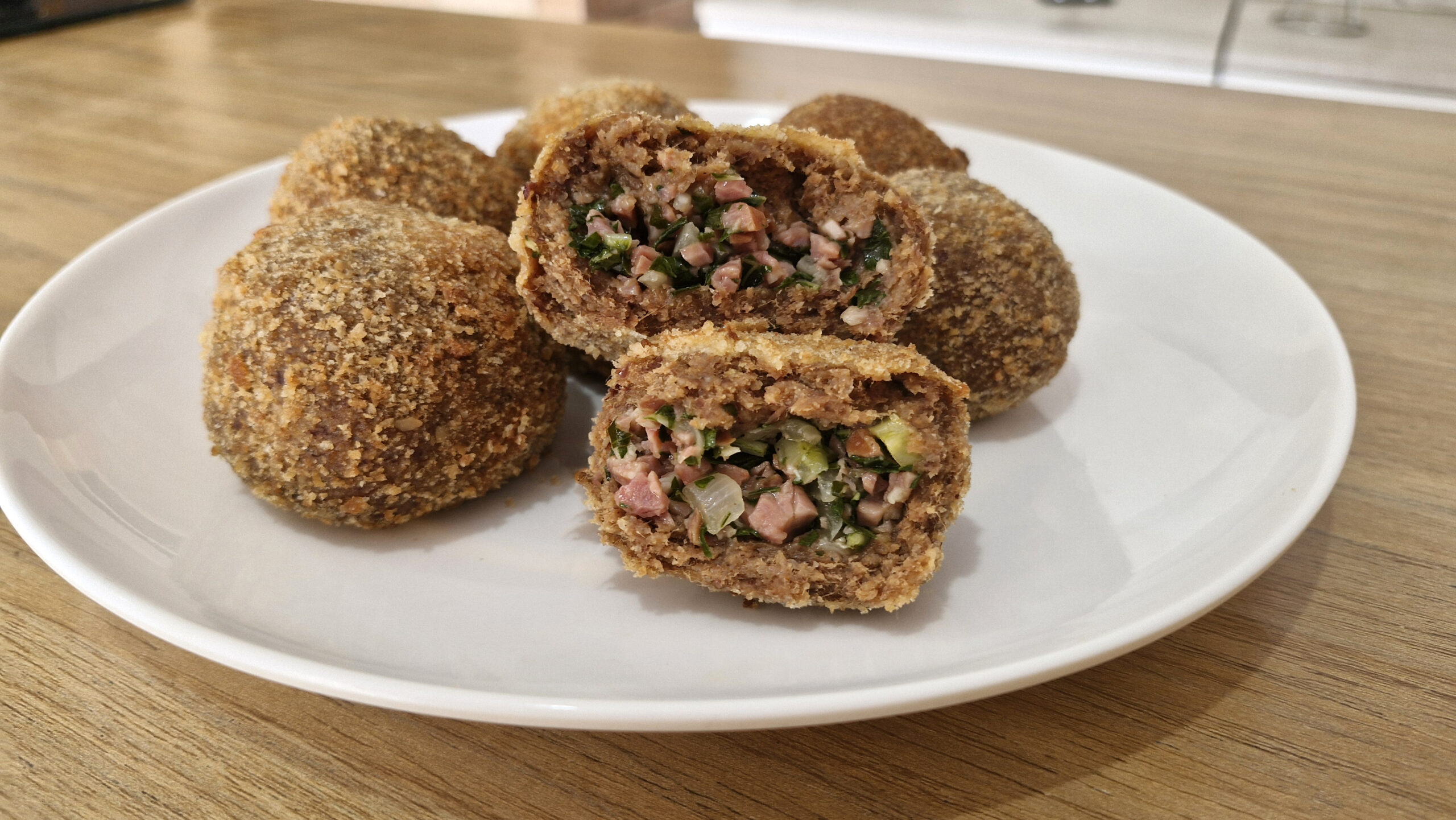 Bolinho de Feijoada Recheado crocante, servido dourado e quentinho em um prato rústico, com calabresa e couve no recheio, acompanhado de molho apimentado.
