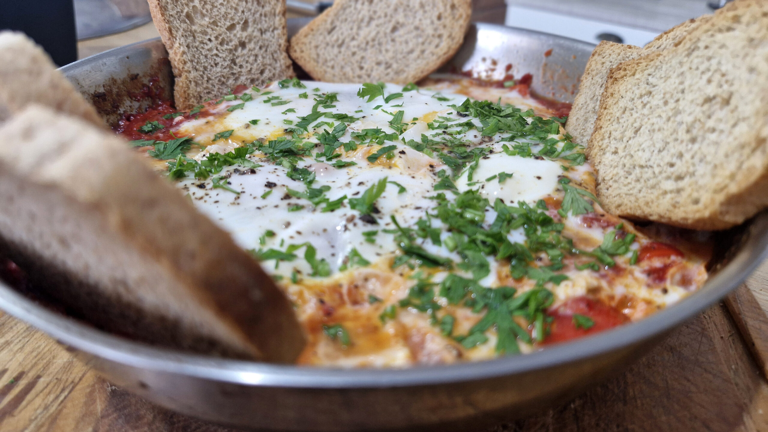 Shakshuka vegetariana servida em frigideira com ovos pochê sobre molho de tomate encorpado