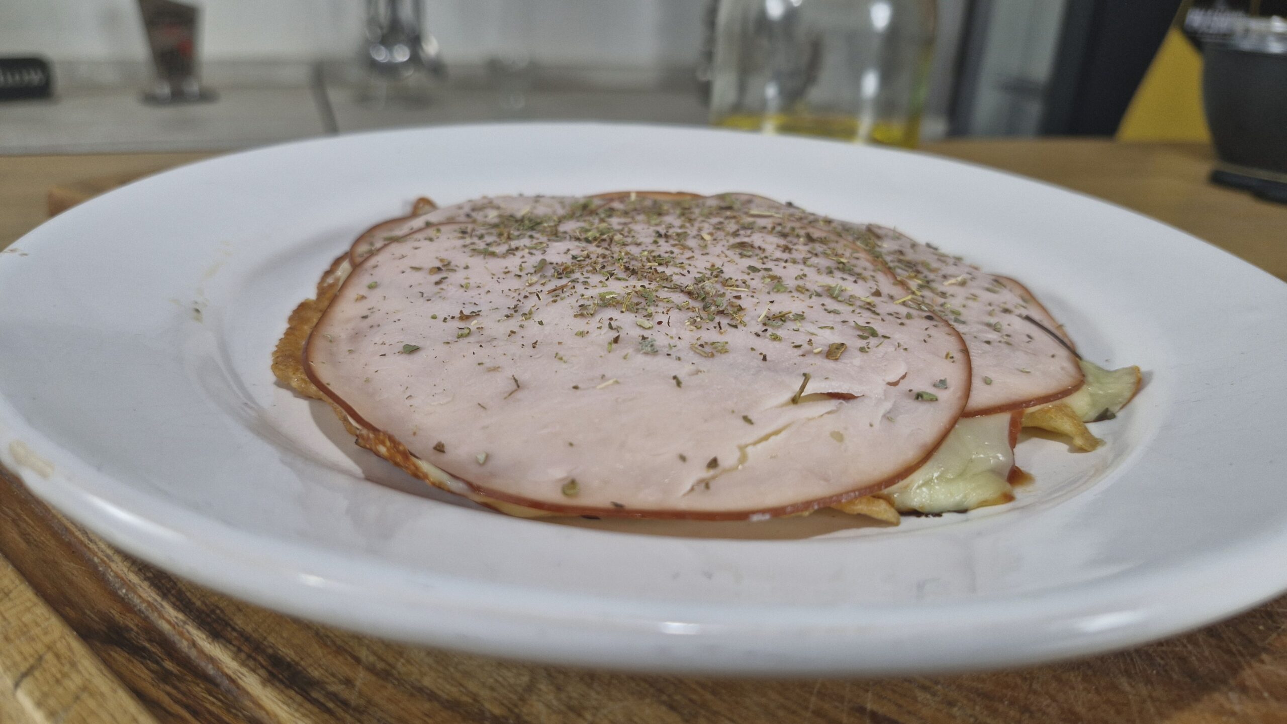 Pizza low carb na frigideira, coberta com queijo derretido, peito de peru e ervas frescas
