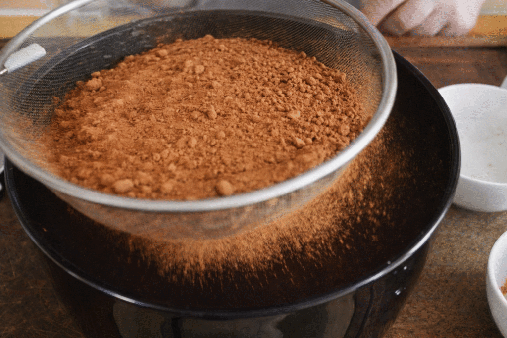 cacau-em-po-sendo-somado-ao-brownie-1024x683 Brownie perfeito: casquinha crocante por fora e massa densa por dentro